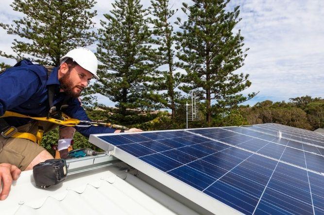 tech installing solar panels on a rooftop